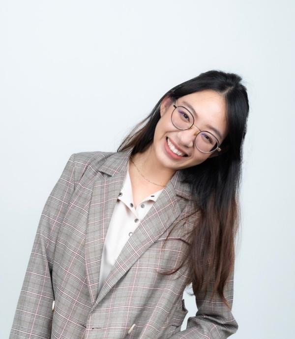 Person smiling wearing glasses and checkered grey suit over white shirt