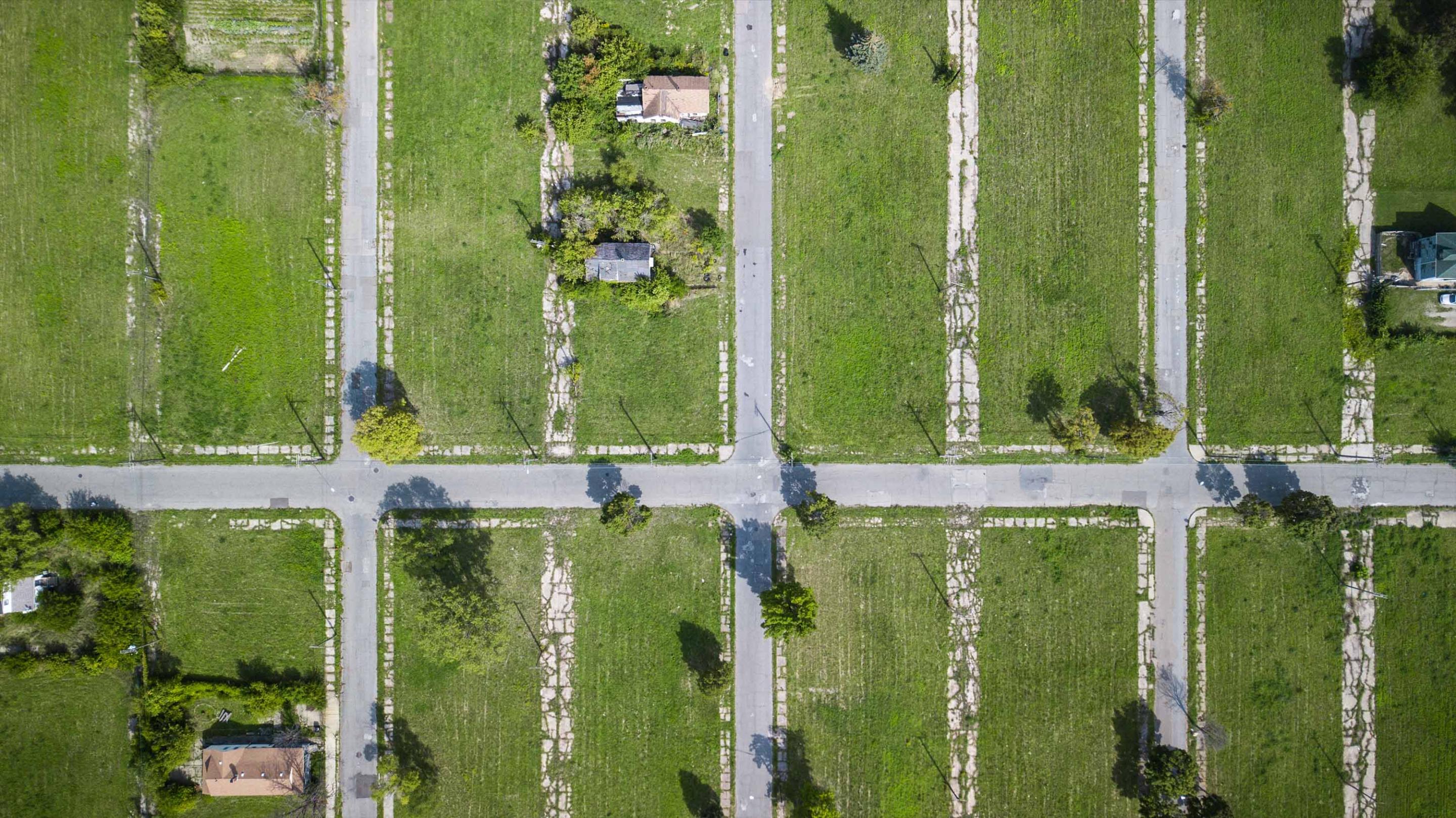Street rows surrounded by grass and 3 houses.