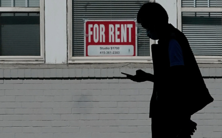 For Rent sign on window with sillhouette of person looking at phone in front