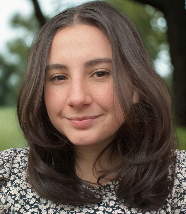 A woman with long brown hair smiles at the camera.