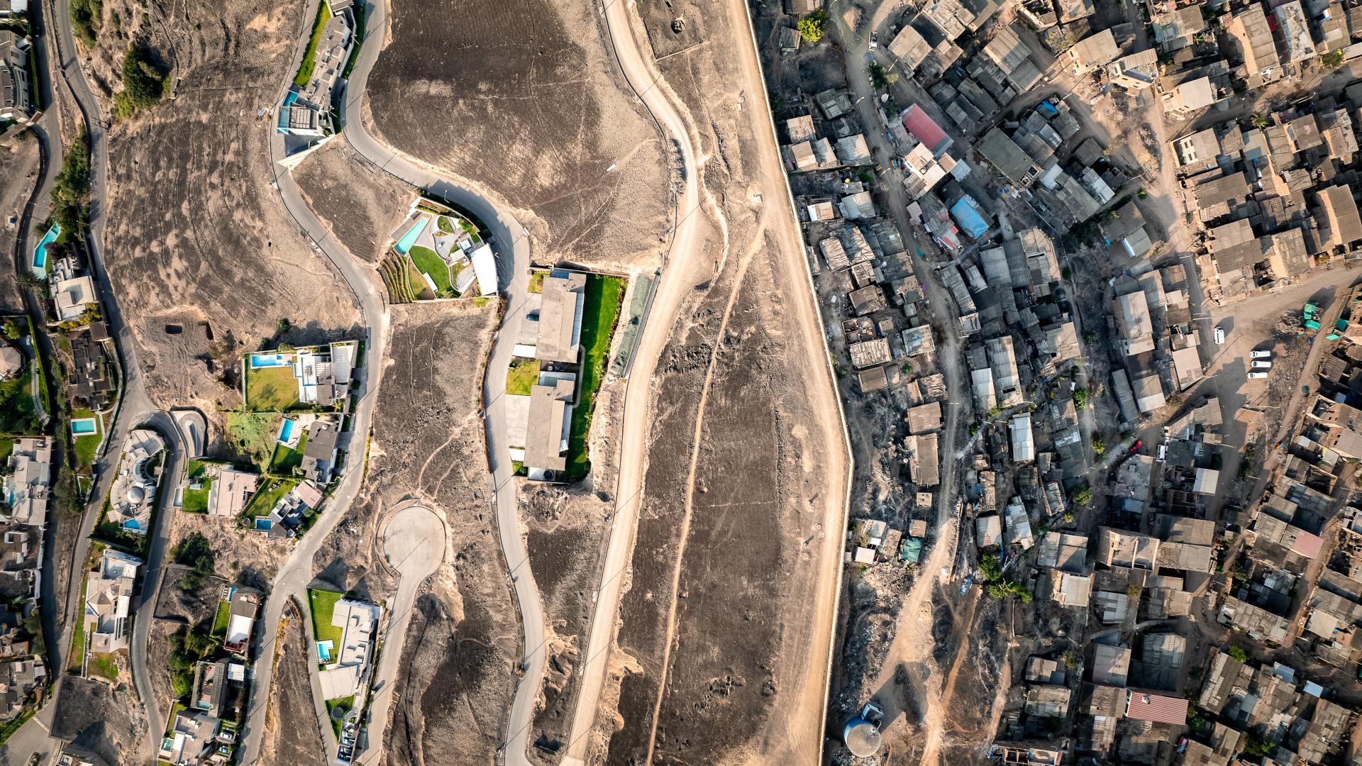 Aerial view of arid hill with mansions on left and low income housing on right